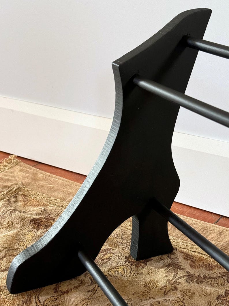 Peut inclure: Un pr&eacute;sentoir &agrave; chaussures en bois noir avec un design incurv&eacute;. Le pr&eacute;sentoir comporte trois barres horizontales pour ranger les chaussures et un panneau lat&eacute;ral incurv&eacute; d&eacute;coratif. Le pr&eacute;sentoir est en bois et peint en noir.
