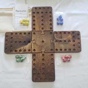May include: A wooden Aggravation board game with four interlocking sections. The game includes marbles in yellow, blue, green, and red. A small bag with the game's instructions is also included. The game is designed for 2-4 players.