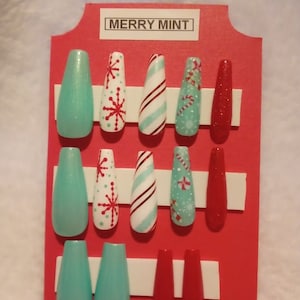 May include: A set of ten false nails with a Christmas theme. The nails are in three colors: red, white, and light blue. The designs include snowflakes, candy canes, and peppermint swirls. The card reads "Merry Mint".