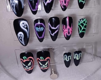 May include: Set of 12 Halloween-themed press-on nails with various designs, including ghosts, bats, spiders, pumpkins, and tombstones. The nails are black with neon green, pink, and purple accents.