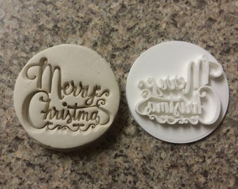 Puede incluir: Un cortador de galletas de plástico blanco con las palabras "Merry Christmas" en una fuente cursiva.