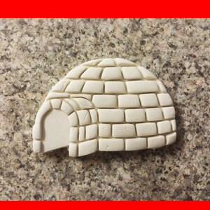 May include: A white ceramic igloo-shaped ornament with a brick pattern. The igloo has a small entrance on the side.