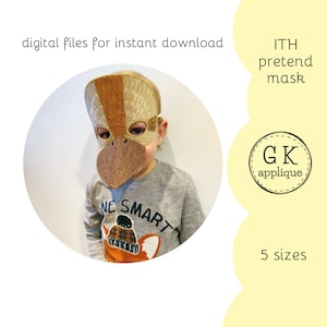 May include: A child wearing a brown and gold felt bird mask with a long beak. The mask is for an in-the-hoop embroidery project. The text "ITH pretend mask" and "GK applique" are visible in the image.