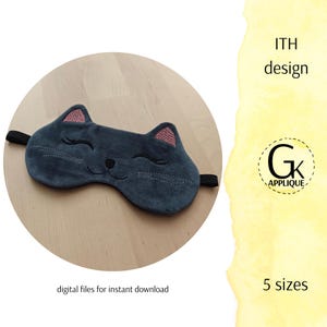 Puede incluir: Una máscara para dormir gris con forma de cara de gato, con detalles bordados. La máscara tiene orejas rosas y una banda elástica negra. El texto "ITH design" y "5 tamaños" son visibles. Las palabras "archivos digitales para descarga instantánea" también son visibles.