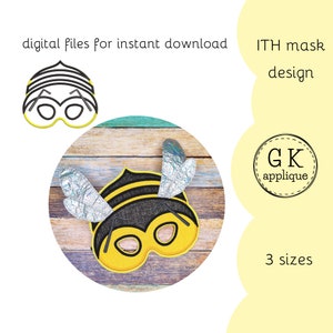 May include: A yellow and black bee mask with silver wings. The mask is on a wooden background. The text "ITH mask design" and "GK applique" are visible in the image. The text "3 sizes" is also visible.