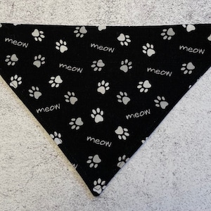 May include: Black bandana with a white paw print and "meow" pattern.