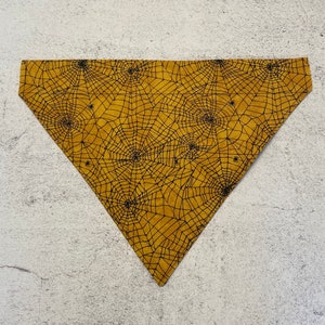 May include: A yellow bandana with a black spiderweb pattern.