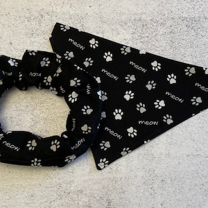 May include: Black and white fabric scrunchie and bandana with a paw print and "meow" pattern.