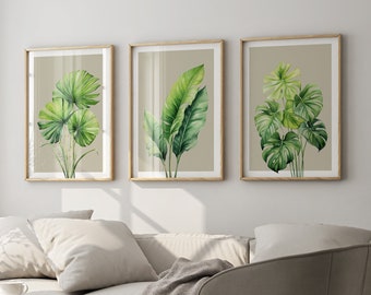 May include: Three framed botanical prints featuring watercolor illustrations of green leaves on a beige background. The prints are hung on a white wall above a light beige sofa and a light beige armchair.