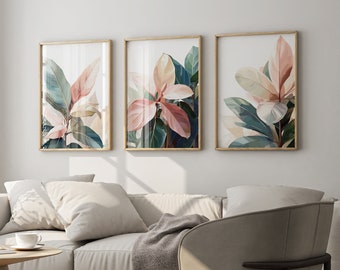 Könnte beinhalten: Drei gerahmte botanische Drucke mit rosa und grünen Blättern an einer weißen Wand über einem hellbeigen Sofa und einem hellbeigen Sessel.