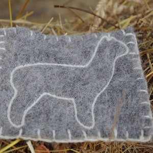 May include: A gray felt square with a white outline of an alpaca, stitched around the edges.