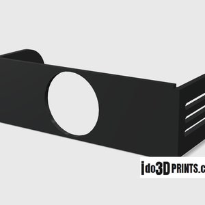 May include: Black plastic wall mount with a round cutout and three slots. The mount is designed to hold a device or object.