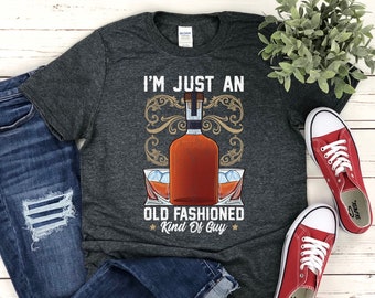 May include: A dark gray t-shirt with the text "I'm just an old fashioned kind of guy" and a graphic of a bottle of whiskey and two glasses with ice cubes.