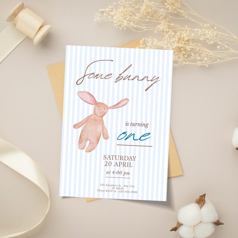 May include: A light blue and white striped invitation card with the text "Some bunny is turning one". The card features a watercolor illustration of a pink bunny and event details.