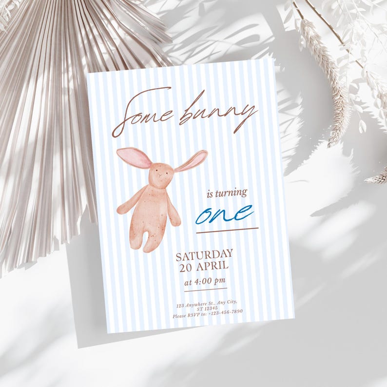 May include: A baby shower invitation with a watercolor illustration of a stuffed bunny. The invitation has a blue and white striped background and reads "Some bunny is turning one" with event details.
