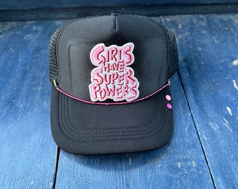 ""Girls Have Super Powers"" Trucker-Kappe."