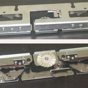 Könnte beinhalten: Nahaufnahme eines silbernen Nähmaschinen-Teils aus Metall mit einer Reihe von Zahnrädern und Hebeln. Das Teil ist aus Metall und hat eine silberne Oberfläche. Das Teil besteht aus zwei Abschnitten, wobei der obere Abschnitt leicht erhöht ist. Der untere Abschnitt hat eine Reihe von Zahnrädern und Hebeln, die sichtbar sind. Das Teil ist in gutem Zustand und scheint funktionsfähig zu sein.