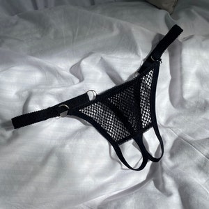 以下が含まれることがあります： シルバーのリングと調節可能なストラップが付いたブラックメッシュランジェリー