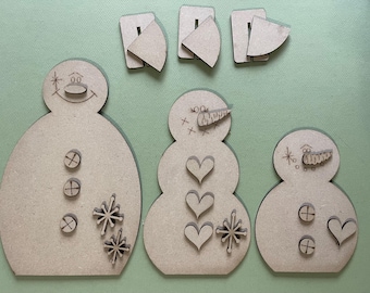Peut inclure: Trois décorations de bonhomme de neige en bois non finies de tailles différentes. Le plus grand bonhomme de neige a trois boutons, deux flocons de neige et une étoile sur son corps. Le bonhomme de neige du milieu a trois cœurs et un flocon de neige sur son corps. Le plus petit bonhomme de neige a deux boutons et un cœur sur son corps. Les trois bonhommes de neige ont un nez de carotte et un visage.