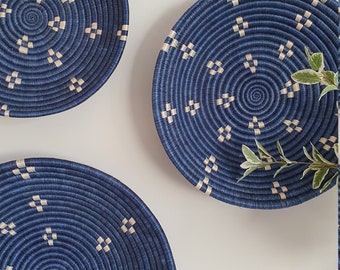 May include: Three blue woven wall baskets with a white geometric pattern. The baskets are round and have a raised rim.