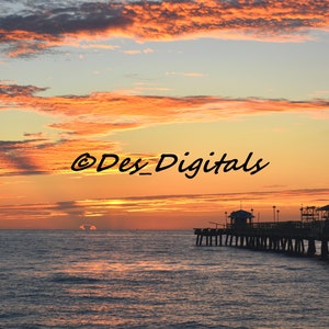 May include: A coastal sunset scene featuring a pier stretching into the sea. The sky is ablaze with orange and pink hues, reflected in the water. The image includes the text "©Des_Digitals".