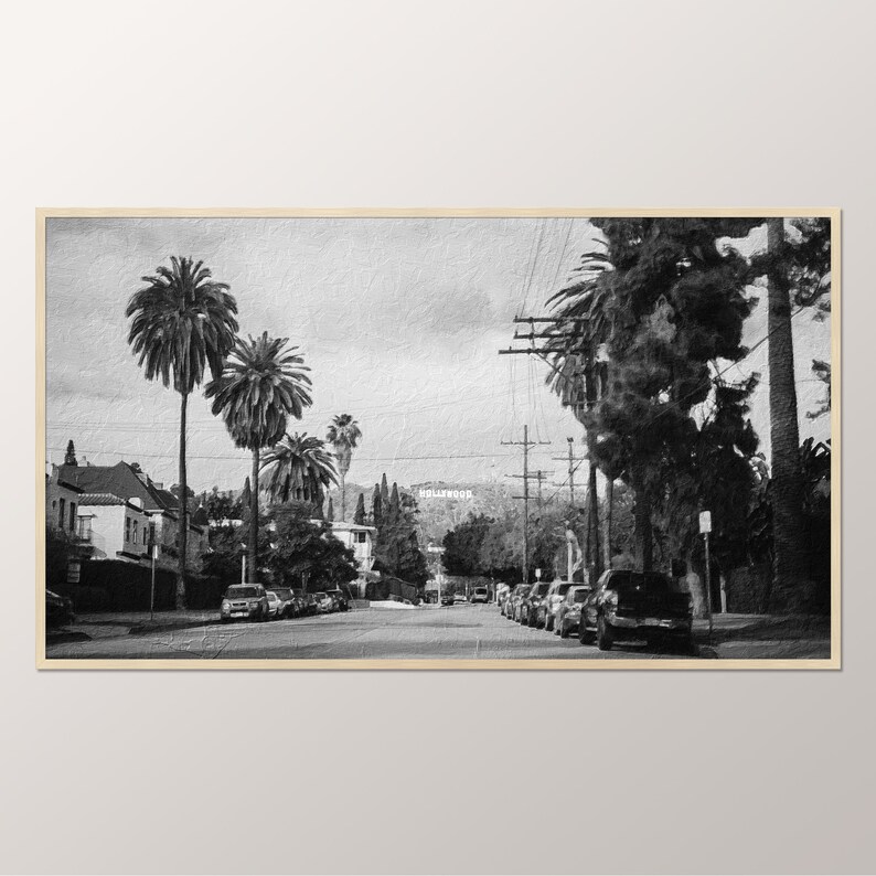 May include: A black and white photograph of a street lined with palm trees and cars. The Hollywood sign is visible in the distance.