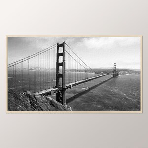 Puede incluir: Una fotograf&iacute;a en blanco y negro del Puente Golden Gate en San Francisco, California. El puente se ve desde la distancia, con el horizonte de la ciudad en el fondo.