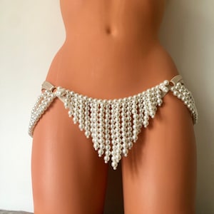 Può includere: Un fondo bikini bianco con frange di perle e un delicato dettaglio di nastro di raso. Le frange sono fatte di piccole perle rotonde che pendono a cascata.