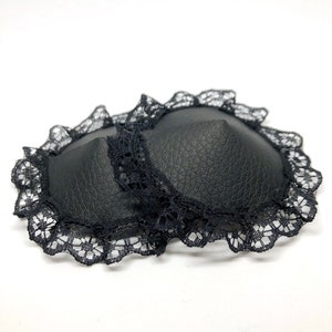 A pair of black faux leather nipple pasties with black lace rim