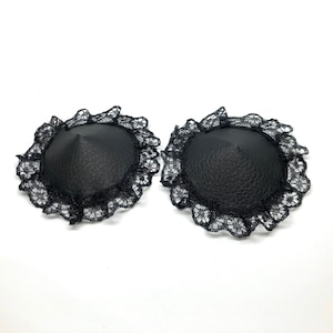 A pair of black faux leather nipple pasties with black lace rim