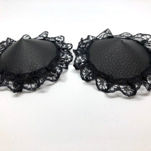 A pair of black faux leather nipple pasties with black lace rim