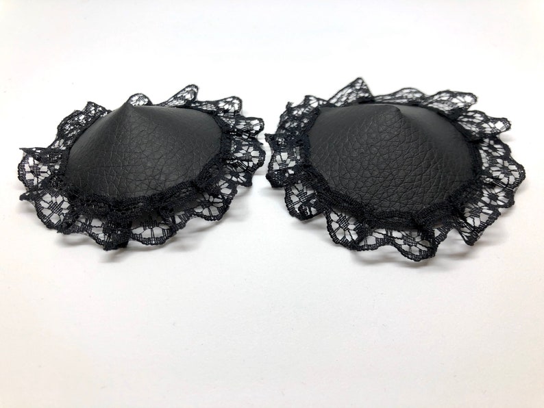 A pair of black faux leather nipple pasties with black lace rim