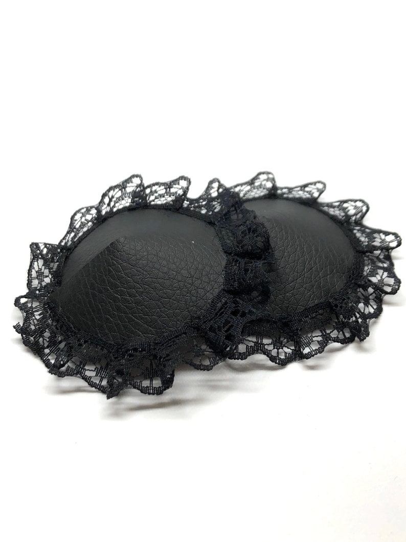 A pair of black faux leather nipple pasties with black lace rim