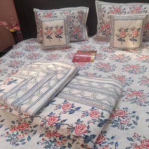 May include: White cotton bedding set with a floral pattern featuring pink and red roses. The set includes a duvet cover, two pillowcases, and a decorative throw pillow.