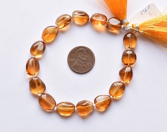May include: A strand of 18.5 inch long, oval-shaped, translucent, amber-colored gemstone beads. The beads are strung on a cord with tassels on each end. A US penny is included for size reference.