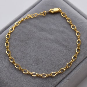 May include: A gold chain bracelet with a lobster clasp closure.