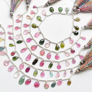 May include: A strand of pink, green and blue gemstone beads with silver accents and colourful tassels. The beads are faceted and have a teardrop shape.