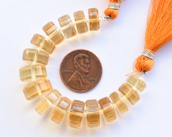 May include: A strand of light yellow and amber faceted gemstone beads, approximately 16 inches long, with two orange tassels. The beads are square shaped and have a polished finish. A US penny is included for size reference.