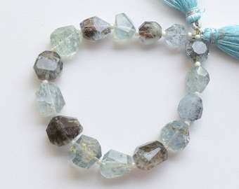 May include: A strand of faceted aquamarine beads with a light blue tassel at each end. The beads are a mix of light and dark blue with a cloudy, translucent appearance.