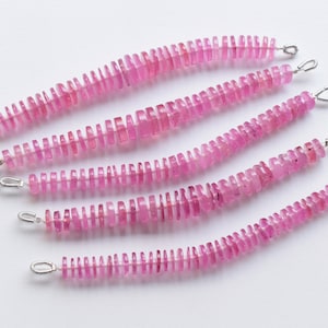 May include: Five strands of pink gemstone beads with silver clasps. Each strand is made of small, rectangular beads.