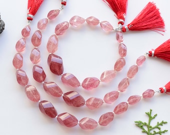 May include: Three strands of faceted pink quartz beads with red tassels on each end. The beads are a light pink color and have a translucent appearance.