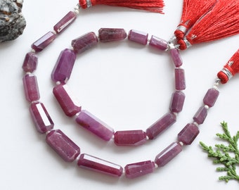May include: A strand of faceted purple gemstone beads with silver clasps and red tassels. The beads are rectangular in shape and have a polished finish.