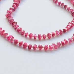 May include: A pink tourmaline and pearl necklace with a delicate design. The necklace is made of small, faceted pink tourmaline beads and tiny white pearls.