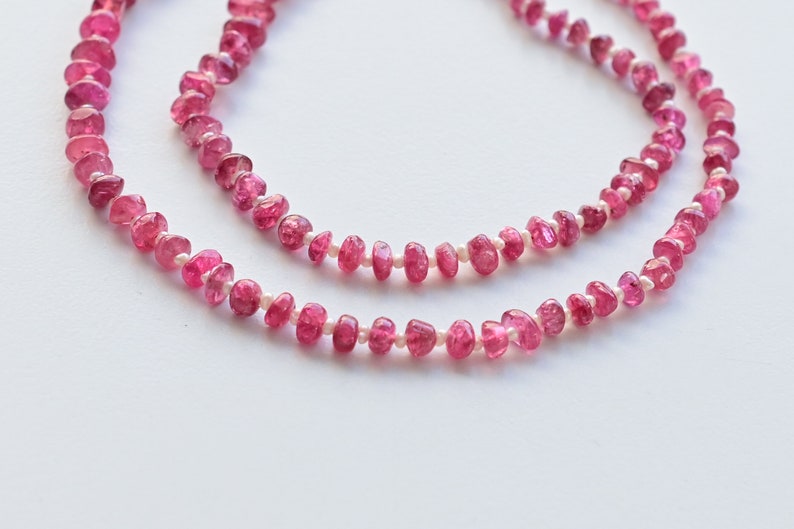 May include: A pink tourmaline and pearl necklace with a delicate design. The necklace is made of small, faceted pink tourmaline beads and tiny white pearls.