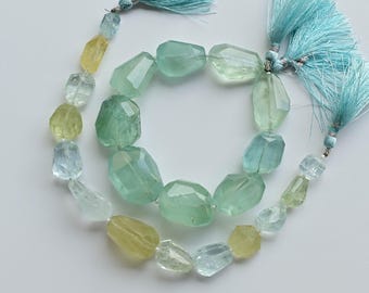 May include: A strand of faceted gemstone beads in shades of yellow, green, and blue. The beads are strung on a cord with tassels at each end.