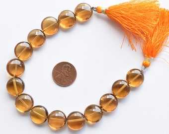 May include: A strand of 18 round, translucent, amber-colored gemstone beads with a tassel. The beads are approximately the size of a US penny.