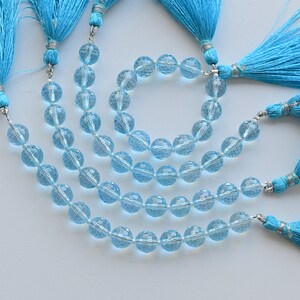 Puede incluir: Un conjunto de tres collares de piedras preciosas azules con borlas turquesas. Los collares est&aacute;n hechos de cuentas redondas facetadas y est&aacute;n enhebrados en un cord&oacute;n plateado.