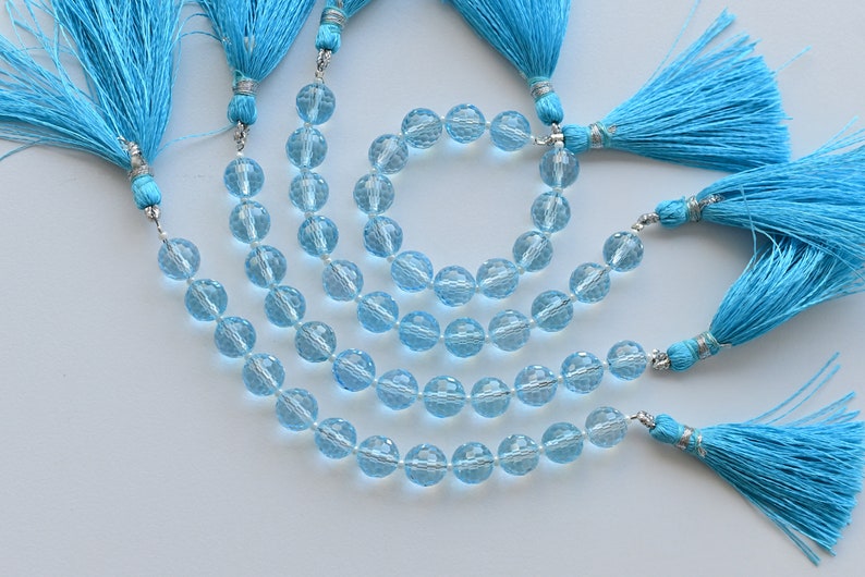 Puede incluir: Un conjunto de tres collares de piedras preciosas azules con borlas turquesas. Los collares est&aacute;n hechos de cuentas redondas facetadas y est&aacute;n enhebrados en un cord&oacute;n plateado.