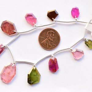 Peut inclure: Un collier de pierres précieuses roses, vertes et brunes sur une chaîne en argent. Les pierres précieuses sont facettées et ont des formes variées. La chaîne est enfilée de petites perles d'argent. Un penny est inclus pour l'échelle. L'étiquette indique "S-1".