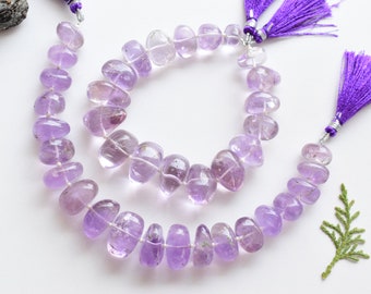 May include: Two strands of amethyst gemstone beads, one longer than the other, with purple tassels at the ends. The beads are a light purple color and have a smooth, polished finish.